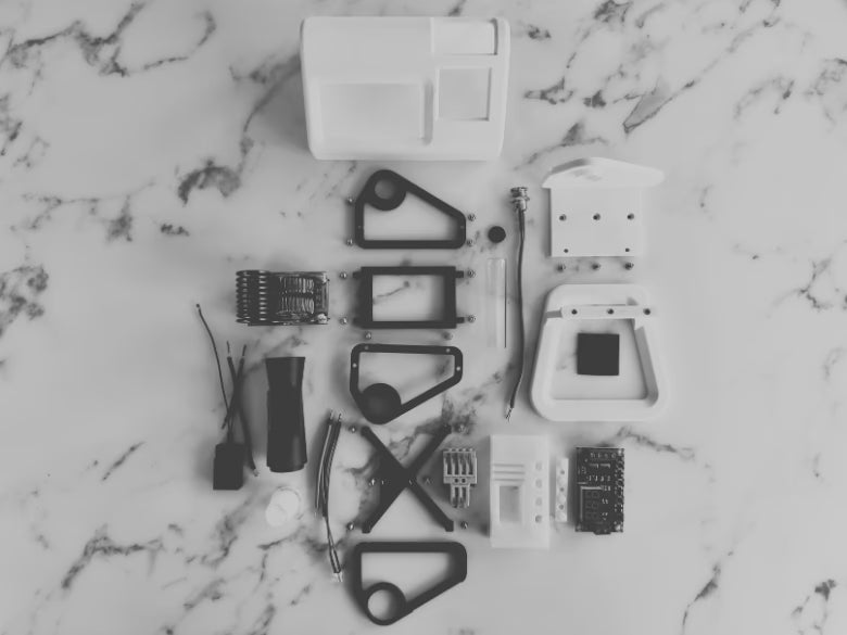 A photo of all the internal parts and pieces of a white mycology and lab tool sterilizer on a white gradient background