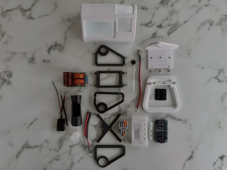 A photo of all the internal parts and pieces of a white mycology and lab tool sterilizer on a white gradient background