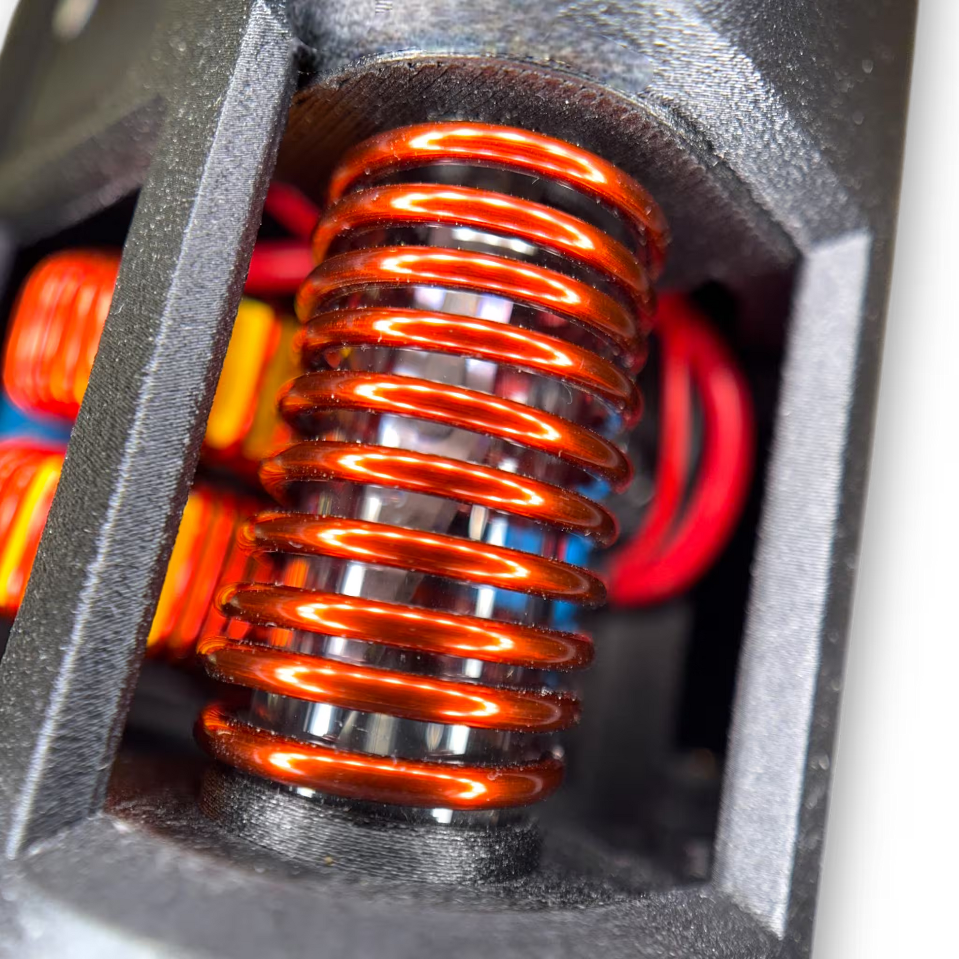 Close-up of a induction coil with red coils inside a black housing.