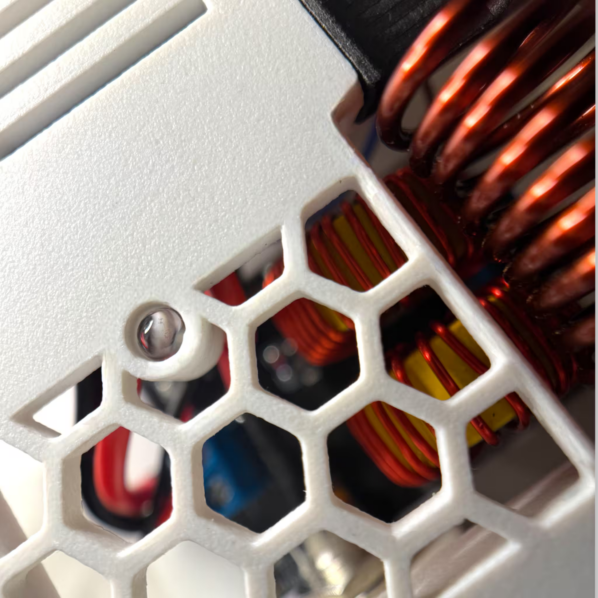 Close-up of automatic induction sterilizer with copper coils and honeycomb pattern on a white housing