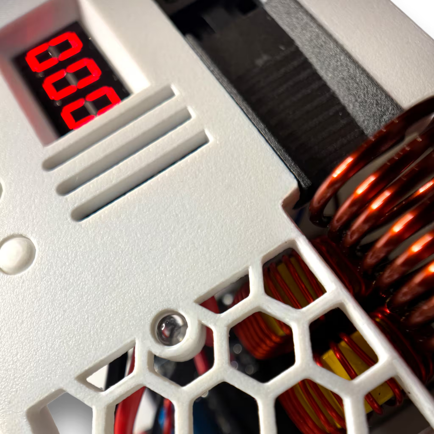 Close-up of a white automatic sterilizer with red LED digital display and a copper coil in the background.